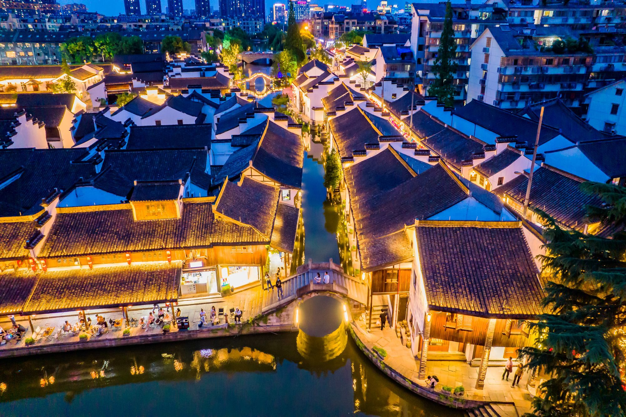 An aerial view of Shaoxing at night, with illuminated buildings and canals.